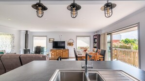 Une cuisine moderne dotée d’un grand îlot central, d’un évier en acier inoxydable et de luminaires suspendus.