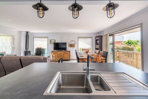 A modern kitchen with a central island, a dining area with a table and chairs, a television, and a fireplace.