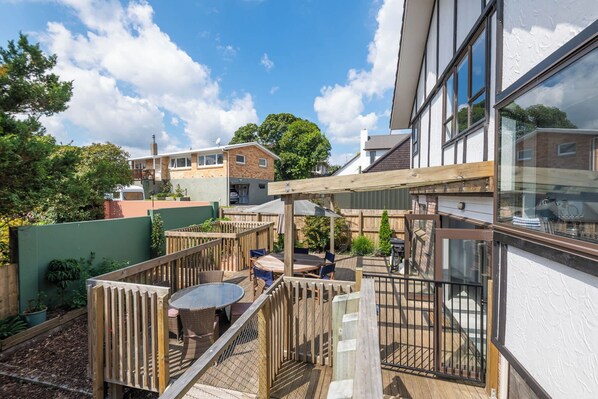 A residential area with a wooden deck, a round table, and chairs.