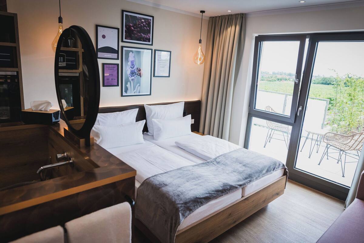A hotel room with a bed, a desk, and a large window with a view of the outdoors.