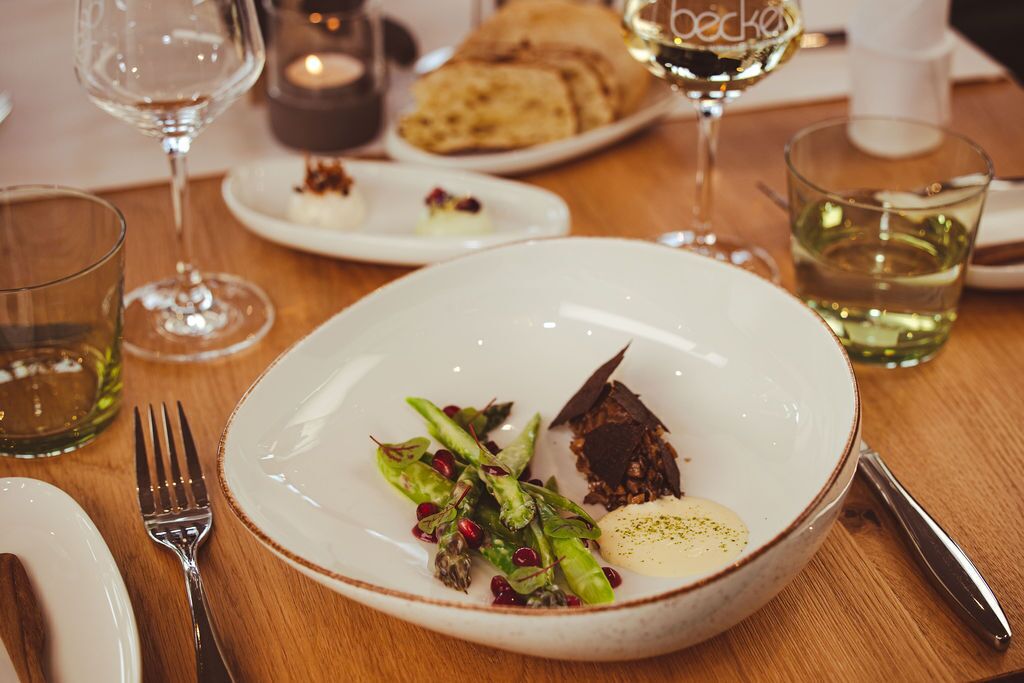 A dining table with a plate of food, a glass of white wine, and a candle.