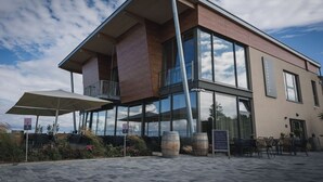 Un edificio moderno con amplios ventanales y una zona de estar exterior cubierta.
