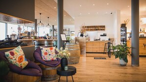 Un interior moderno con barriles de madera como asientos, un mostrador de recepción y una cocina a la vista.