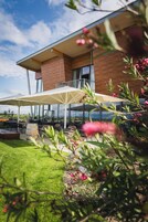 A modern building with a balcony, outdoor seating, and a view of the landscape.