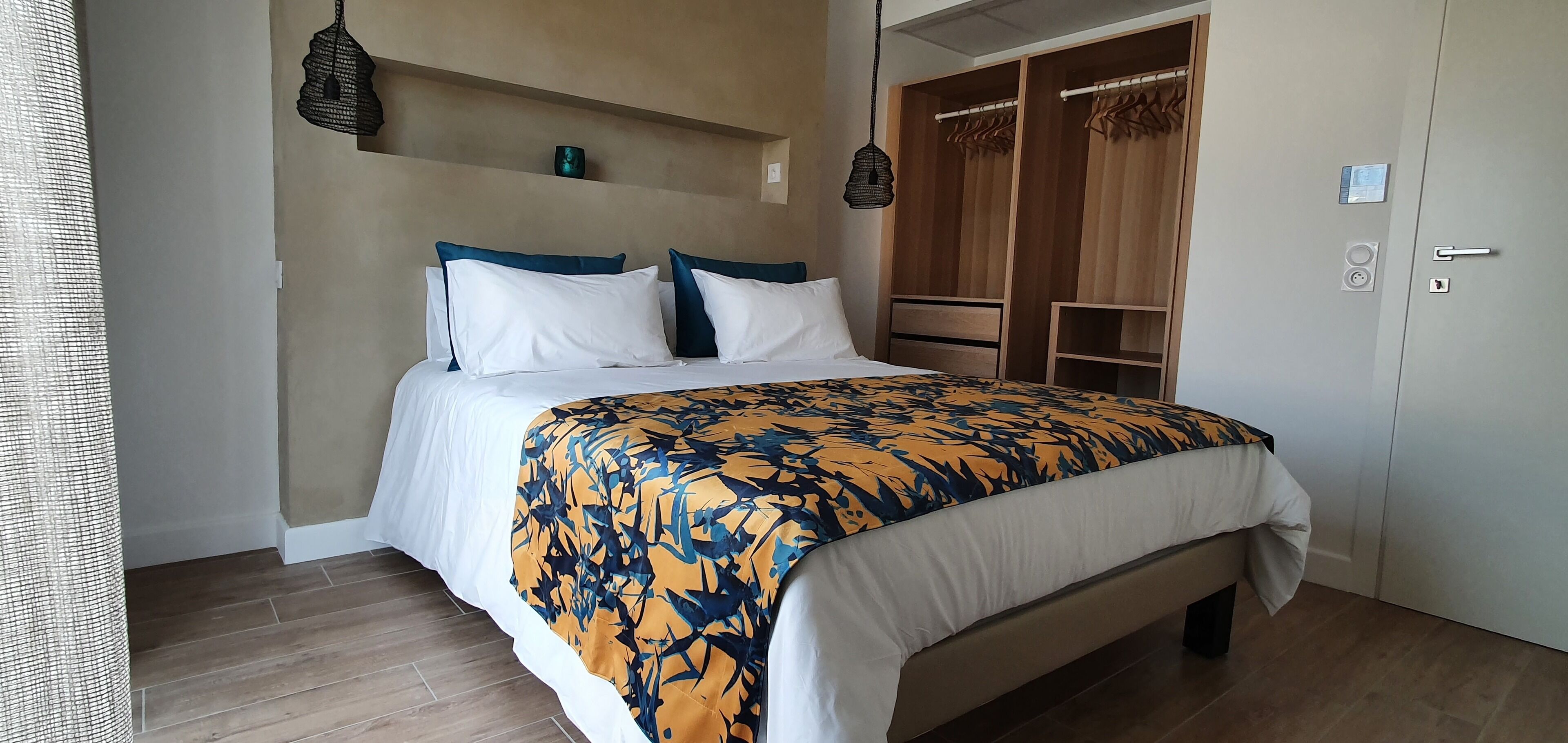 A bedroom with a bed, a wardrobe, and a hanging light fixture.
