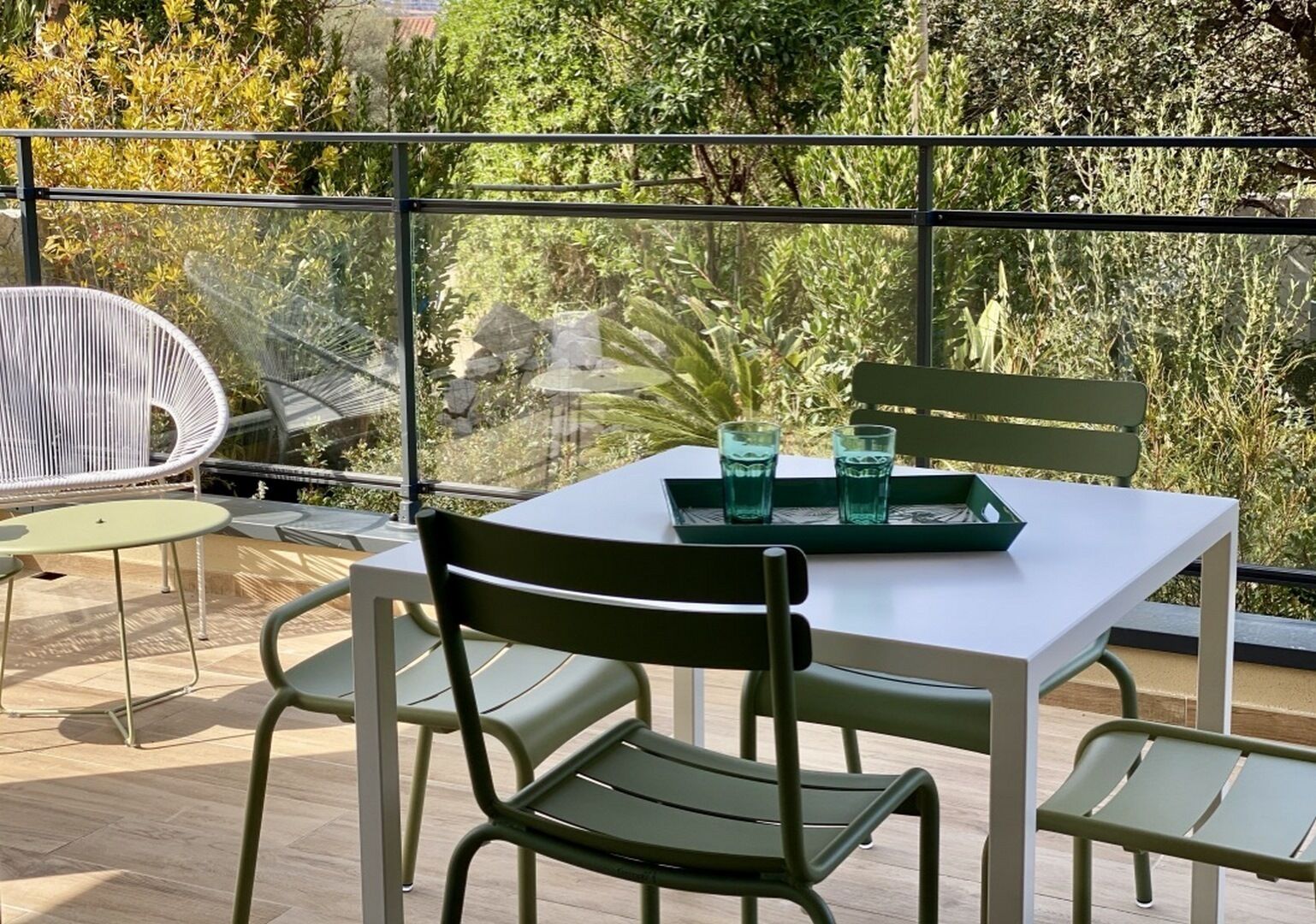 Ein Balkon mit Tisch, Stühlen, zwei Gläsern Wasser und einer Ablagefläche.