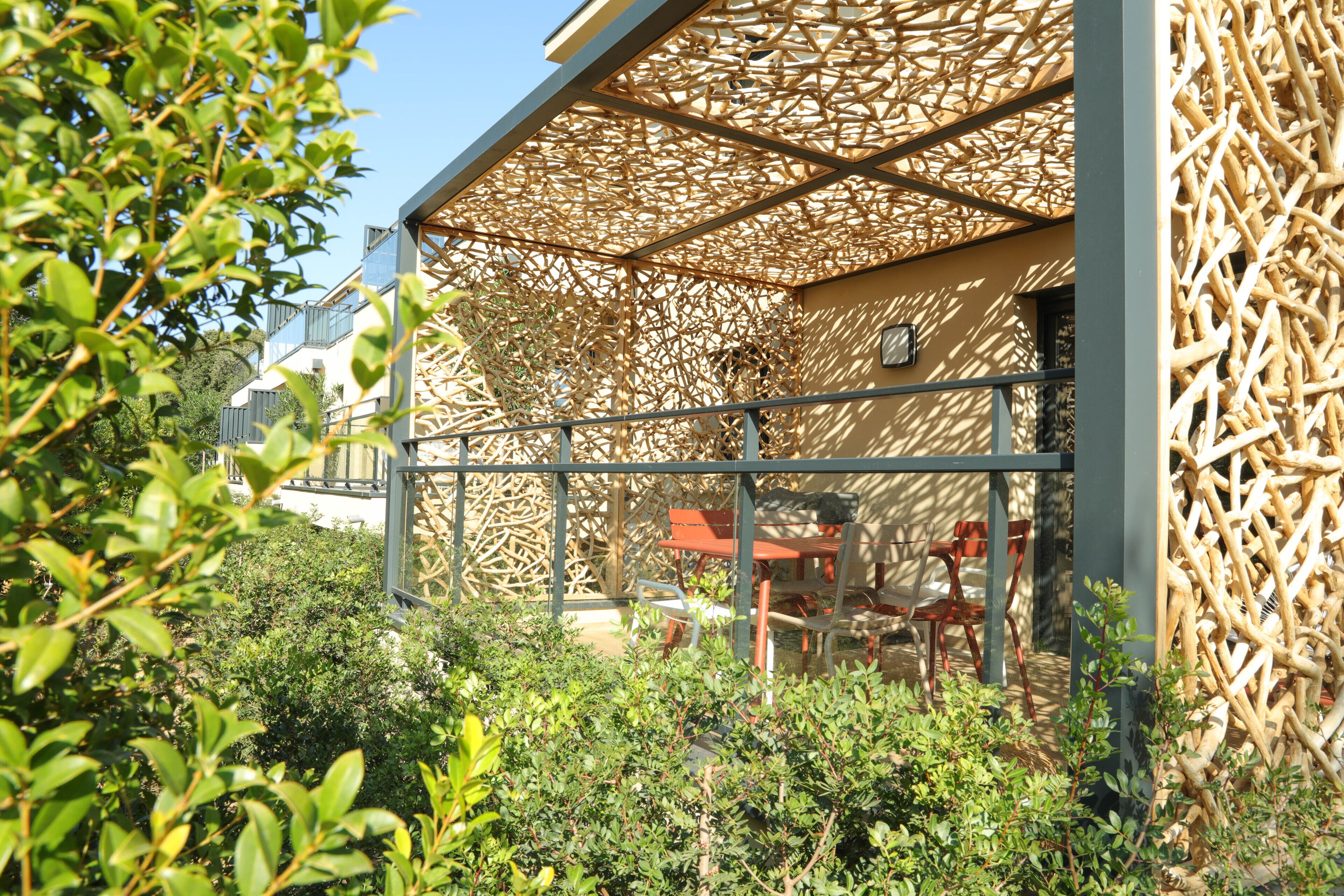 A modern building with a wooden lattice structure, outdoor seating, and greenery.