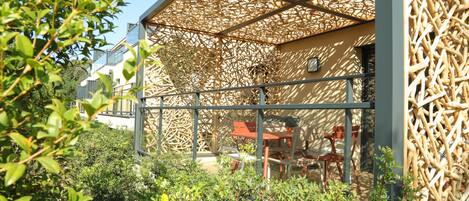 A modern building with a wooden lattice structure, outdoor seating, and greenery.