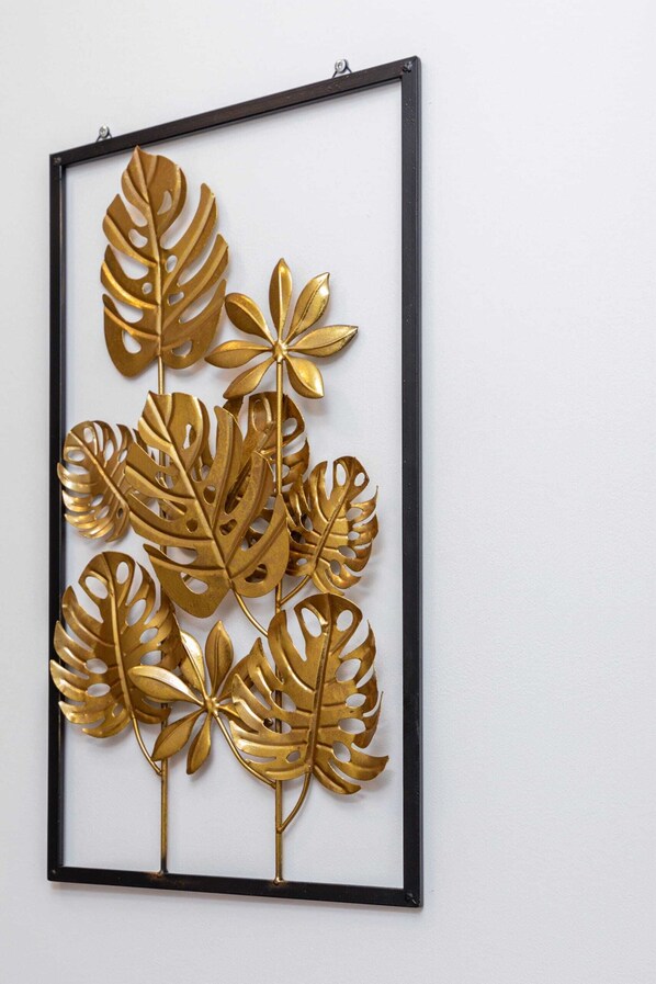 A framed artwork of gold-colored leaves.