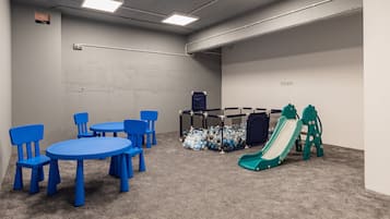 Children can play and climb on the central structure, surrounded by tables and chairs.