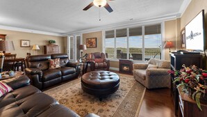A living room with a ceiling fan, leather sofas, a patterned rug, and a fireplace. - Lake View Retreat Near SDC with Free Tickets, Community Outdoor Pool & Upgraded Kitchen (Branson)