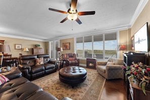 A spacious living room with a ceiling fan, leather furniture, a fireplace, and large windows with blinds. - Lake View Retreat Near SDC with Free Tickets, Community Outdoor Pool & Upgraded Kitchen (Branson)