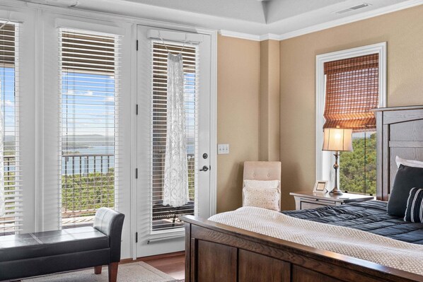 A bedroom with a bed, a nightstand, a lamp, a chair, and a view through a door.
