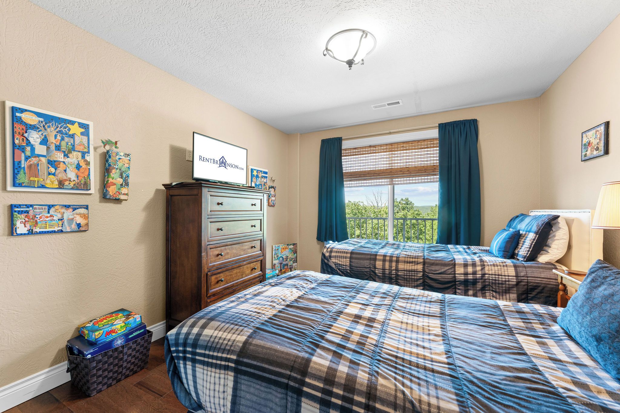 A bedroom with two beds, a dresser, and a window with curtains.