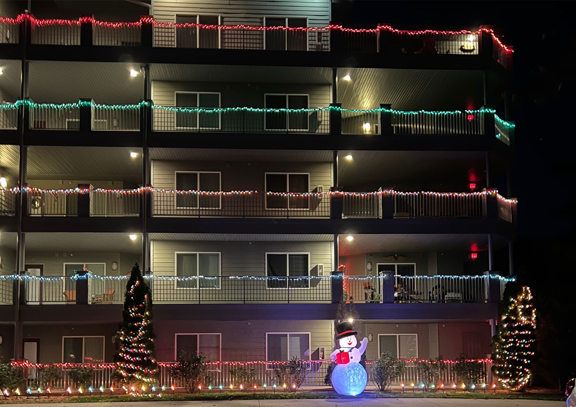 A multi-story building with balconies decorated with colorful lights.