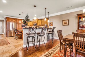 A kitchen with wooden cabinets, stainless steel appliances, and a central island with bar stools. - Lake View Retreat Near SDC with Free Tickets, Community Outdoor Pool & Upgraded Kitchen (Branson)