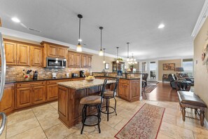 A spacious kitchen with wooden cabinets, a central island with bar stools, and pendant lighting. - Lake View Retreat Near SDC with Free Tickets, Community Outdoor Pool & Upgraded Kitchen (Branson)