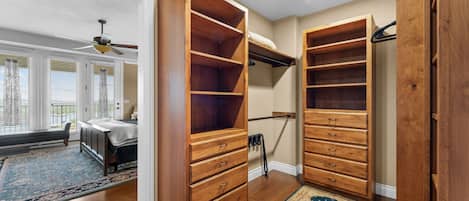 Ein Zimmer mit großem Holzschrank, einem Bett mit Kopfteil, einem Deckenventilator und Blick ins Freie durch ein Fenster mit Jalousien.