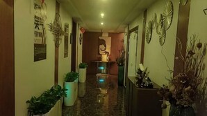 A hallway with potted plants, a reception desk, and wall decorations. - Four Seasons Qingteng Hotel (Outlet Airport) (Ningbo)