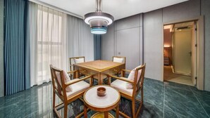 A dining area with a wooden table and chairs, a modern pendant light, and a view of a hallway. - Four Seasons Qingteng Hotel (Outlet Airport) (Ningbo)