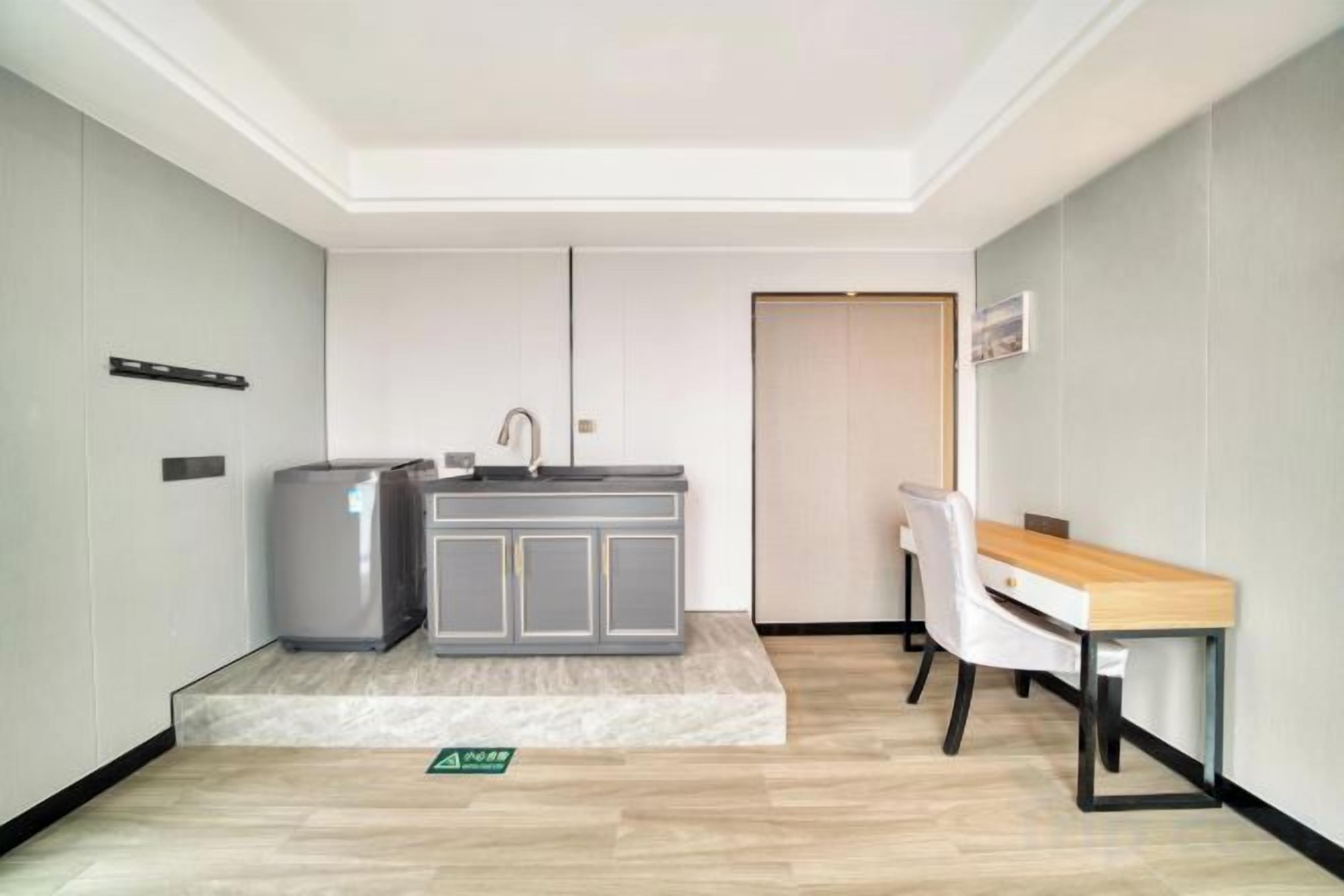 Habitación de hotel compacta con kitchenette, comedor y puerta que da a otra habitación.