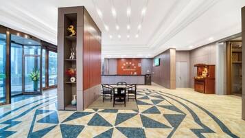 A hotel lobby with a reception desk, a seating area, and a patterned floor.