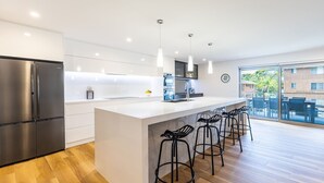 A modern kitchen with a large island, stainless steel appliances, and bar stools. - 5 Kingfisher, 5-7 Ondine Close, Nelson Bay, luxury apartment with Wifi and air conditioning (Nelson Bay)