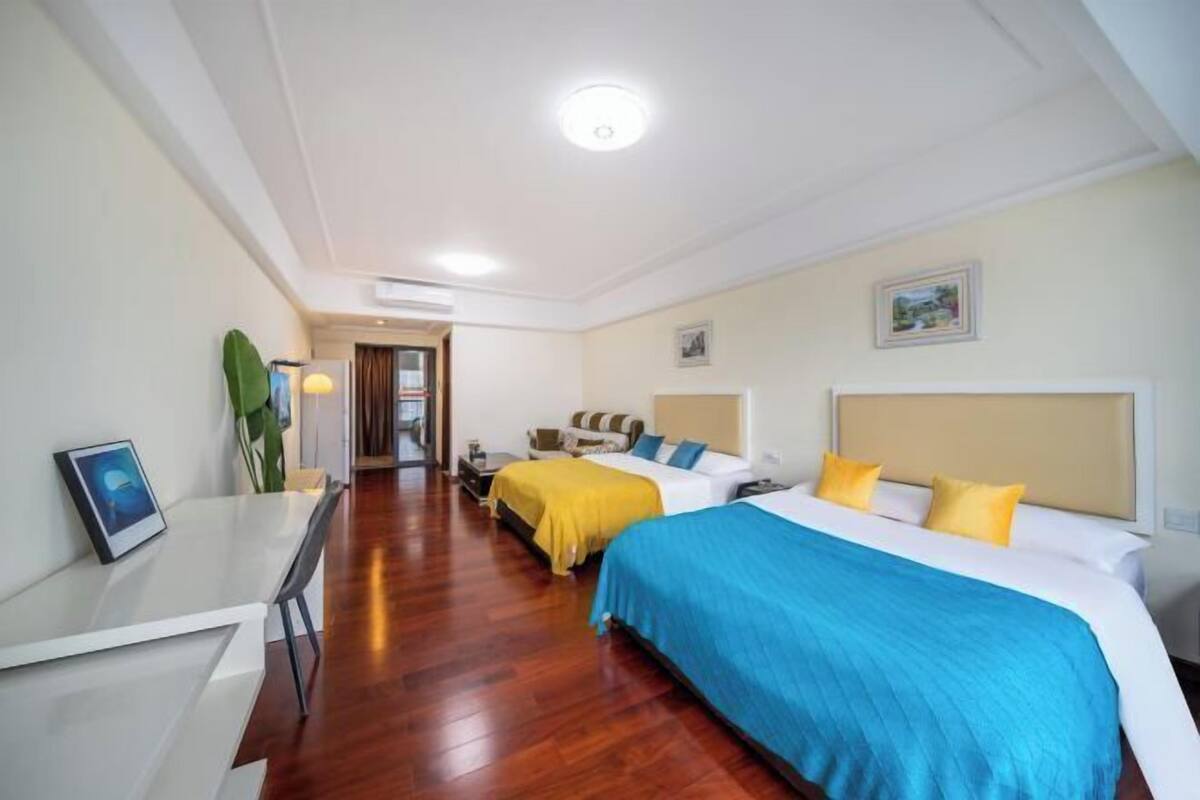 A hotel room with two beds, a desk, and a chair.