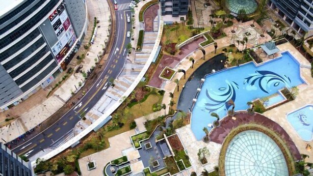 A modern urban complex with a central swimming pool, landscaped gardens, and a curved road. - Tianqin Mushang Hotel Apartment (Huizhou Kaisa Plaza) (Huizhou)