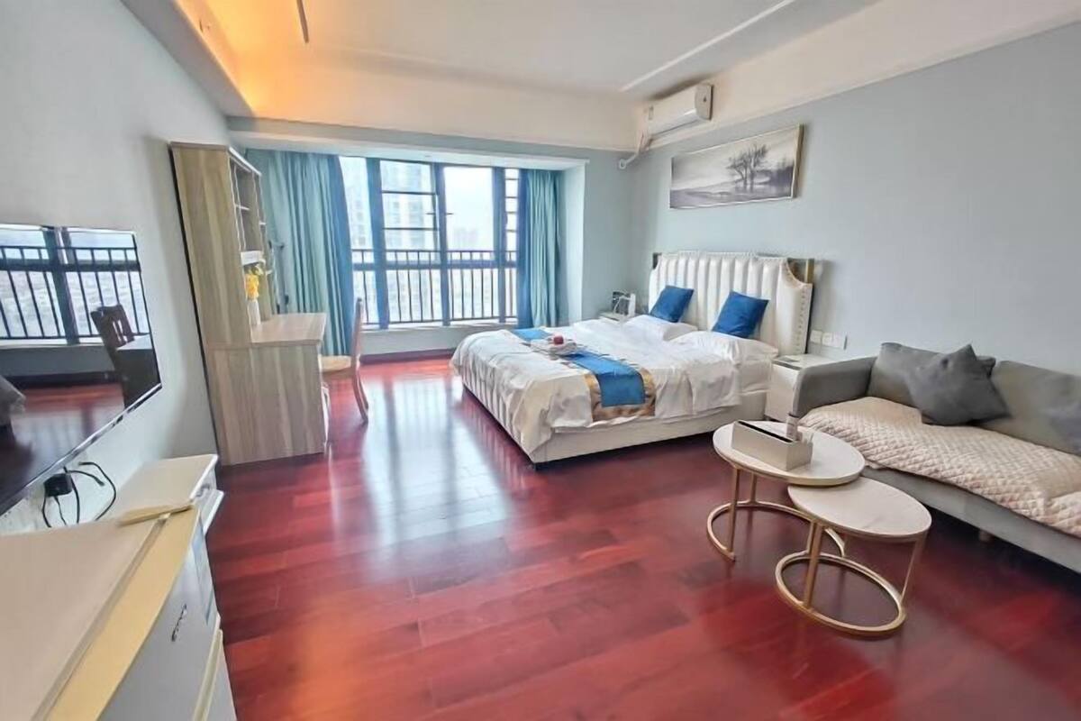 A hotel room with a bed, a sofa, a small table, and a TV.
