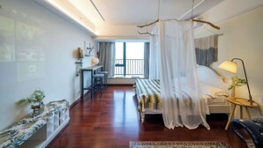 A bedroom with a bed, bedside table, lamp, and a view of the outside. - Tianqin Mushang Hotel Apartment (Huizhou Kaisa Plaza) (Huizhou)