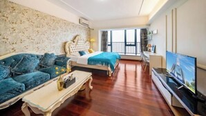A hotel room with a bed, a sofa, a TV, and a balcony with a railing. - Tianqin Mushang Hotel Apartment (Huizhou Kaisa Plaza) (Huizhou)