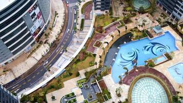 Una piazza moderna in città, con una grande vasca d'acqua circolare, una strada a curva e edifici circostanti.