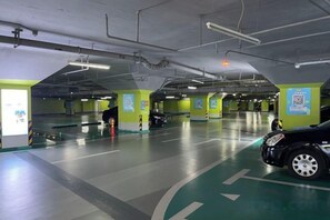 An indoor parking garage with multiple parking spaces, marked lanes, and a QR code on the wall.