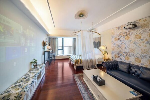A modern hotel room with a bed, a sofa, a coffee table, a desk, and a large window. - Tianqin Mushang Hotel Apartment (Huizhou Kaisa Plaza) (Huizhou)