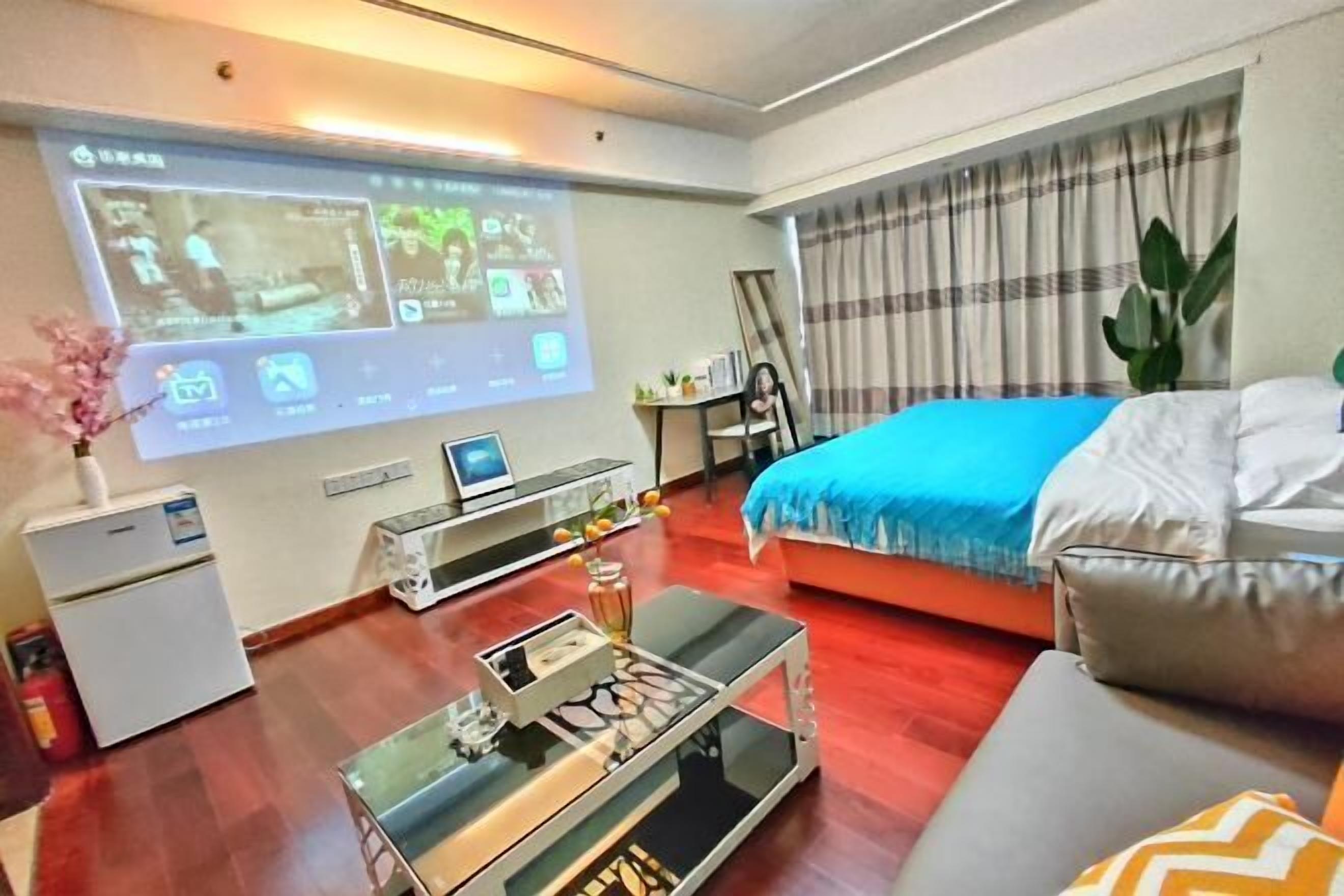 Une chambre d’hôtel équipée d’un lit, d’un écran de télévision diffusant du contenu, d’un petit bureau et d’une table basse.