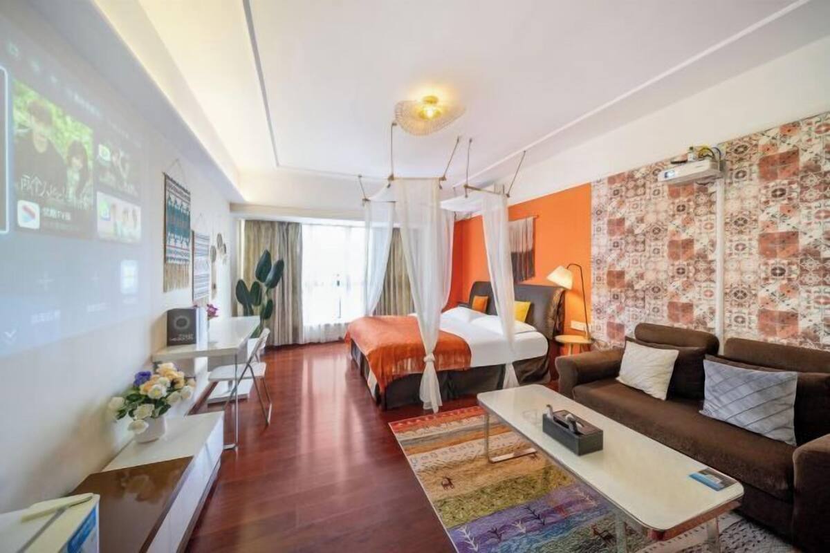 A hotel room with a bed, a sofa, a coffee table, a TV, and a desk with a computer.
