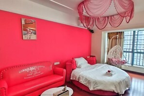 A room with a red sofa, a bed with a white bedspread, a hanging chair, and a large window with curtains. - Tianqin Mushang Hotel Apartment (Huizhou Kaisa Plaza) (Huizhou)