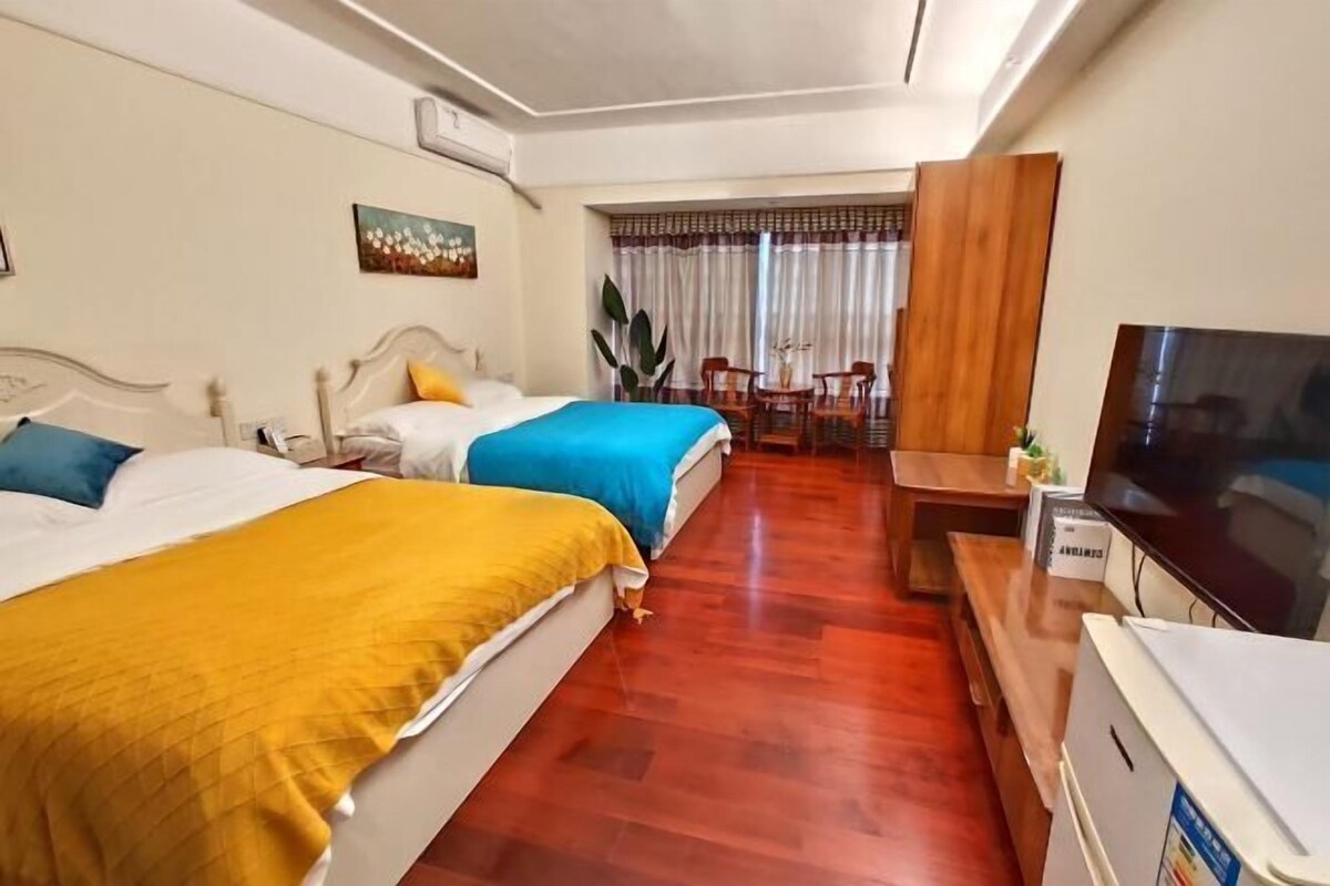 A hotel room with two beds, a TV, a desk, and a chair.