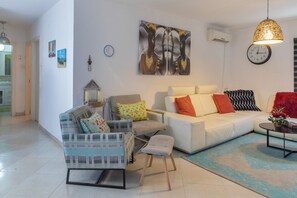 A modern living room with a sofa, armchairs, a coffee table, and a rug.