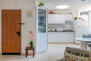 A modern kitchen with white cabinets, a small dining table, and a wooden door. - The private house 5 (beer sheva)