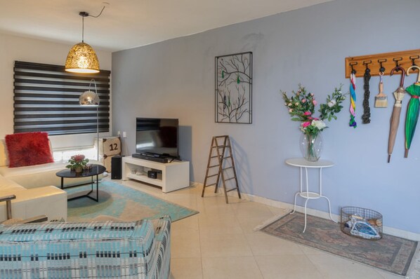 A living room with a TV, sofa, coffee table, and a decorative vase.