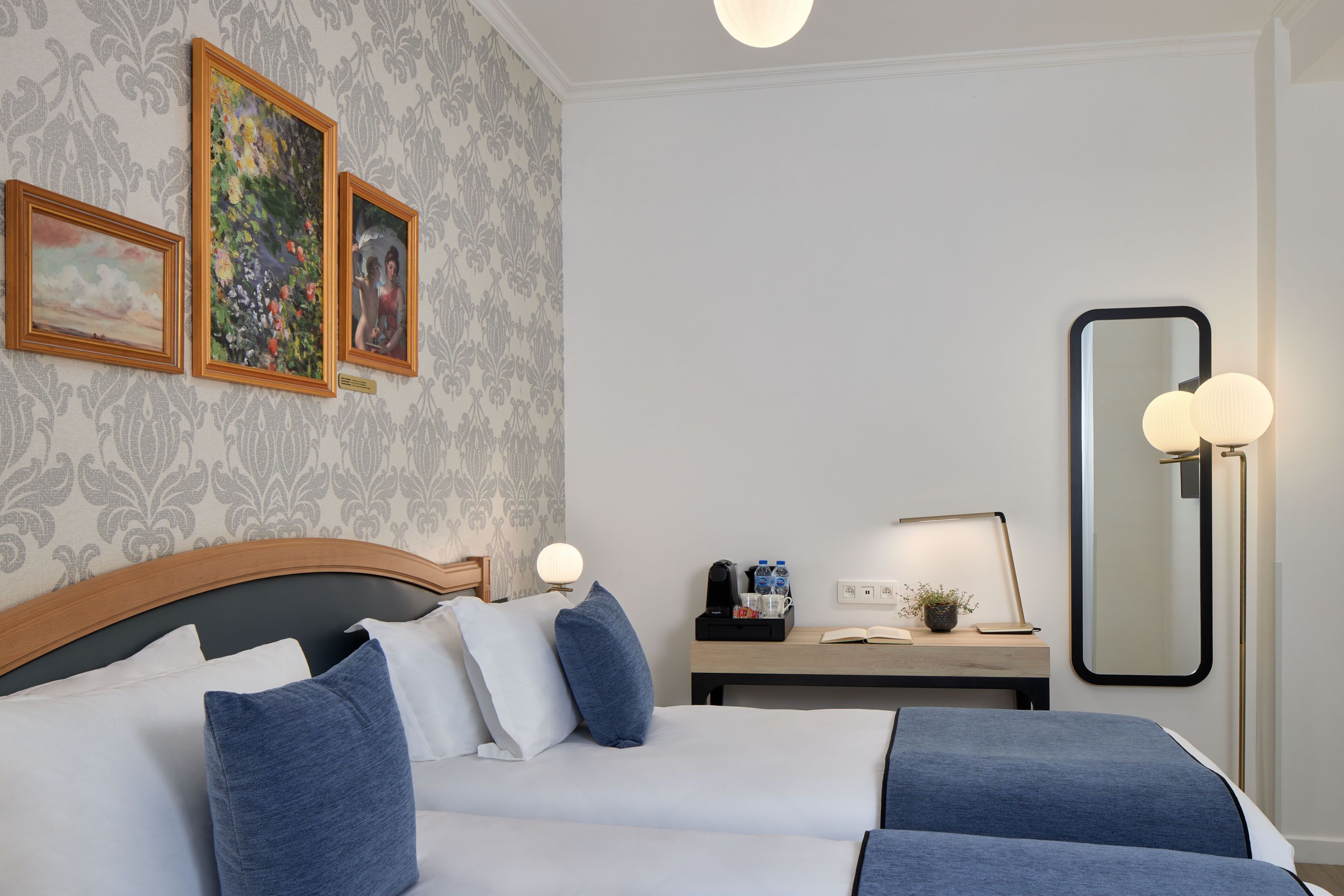 A hotel room with a bed, bedside table, lamp, and wall-mounted artwork.