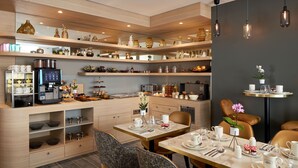 Una cocina moderna con varios estantes, una cafetera y un comedor con una mesa dispuesta para dos personas.