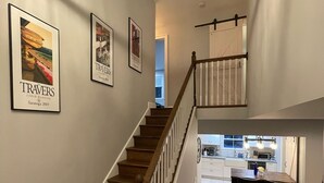 A staircase with wooden steps and white railings leading to a kitchen area with a dining table and chairs.