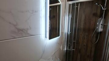 A bathroom with a white sink, a mirror, and a shower enclosure.