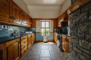 A kitchen with wooden cabinets, a stone wall, and a window.