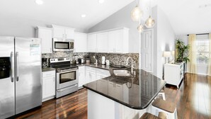 A modern kitchen with white cabinets, stainless steel appliances, a granite countertop, and a wooden floor. - 🐾Pet Friendly-Near Beach-4BR Shore Beats Work🐾 (Miramar Beach)