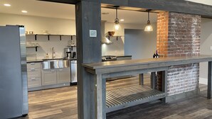 A modern kitchen with a brick accent wall, stainless steel appliances, and pendant lighting. - Riverside Loft with Huge Deck on GAP Trail (Confluence)
