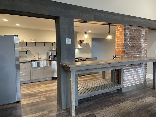 A modern kitchen with a brick accent wall, stainless steel appliances, and pendant lighting.